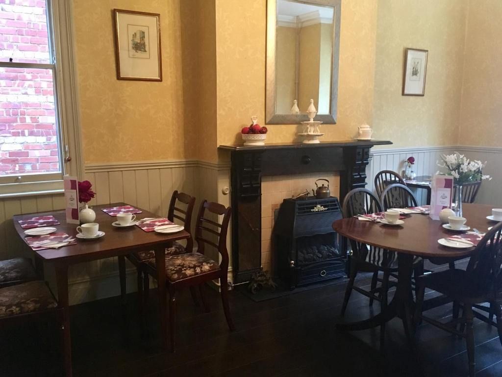 The breakfast room with set tables, a period fireplace and fresh flowers