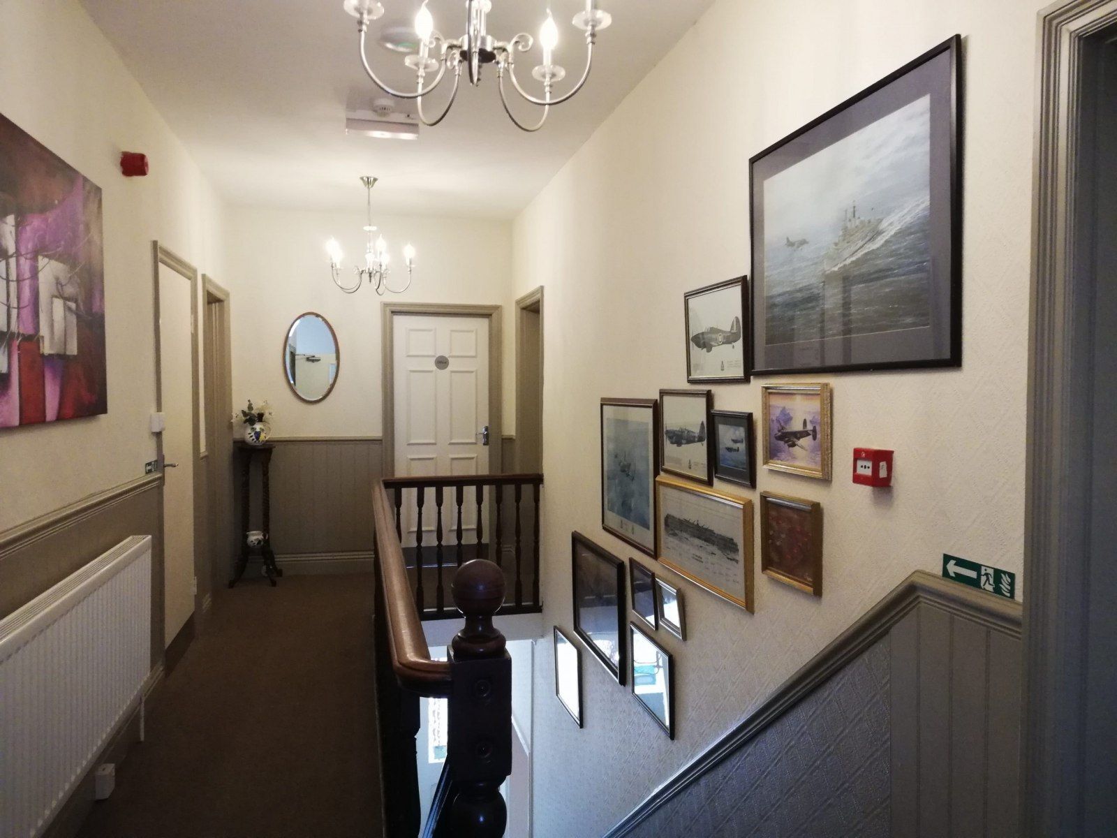 The bright first-floor landing with chandeliers and framed prints