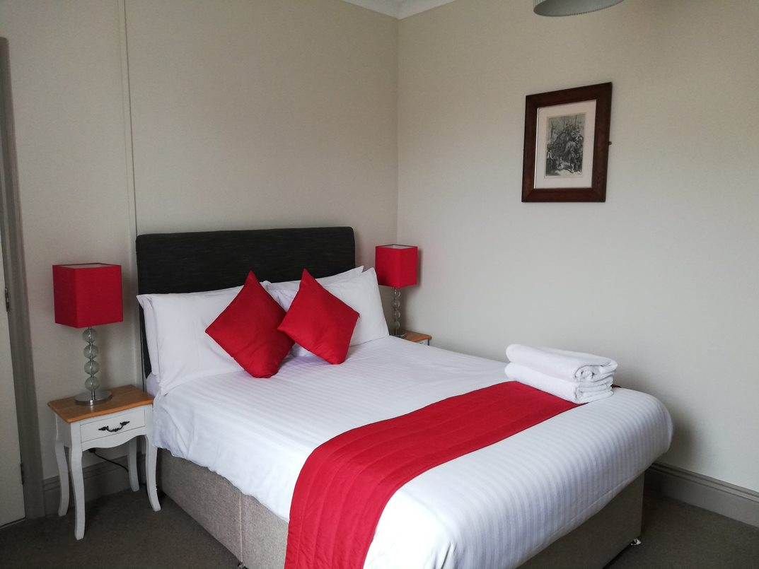 Room with white linen and red cushions