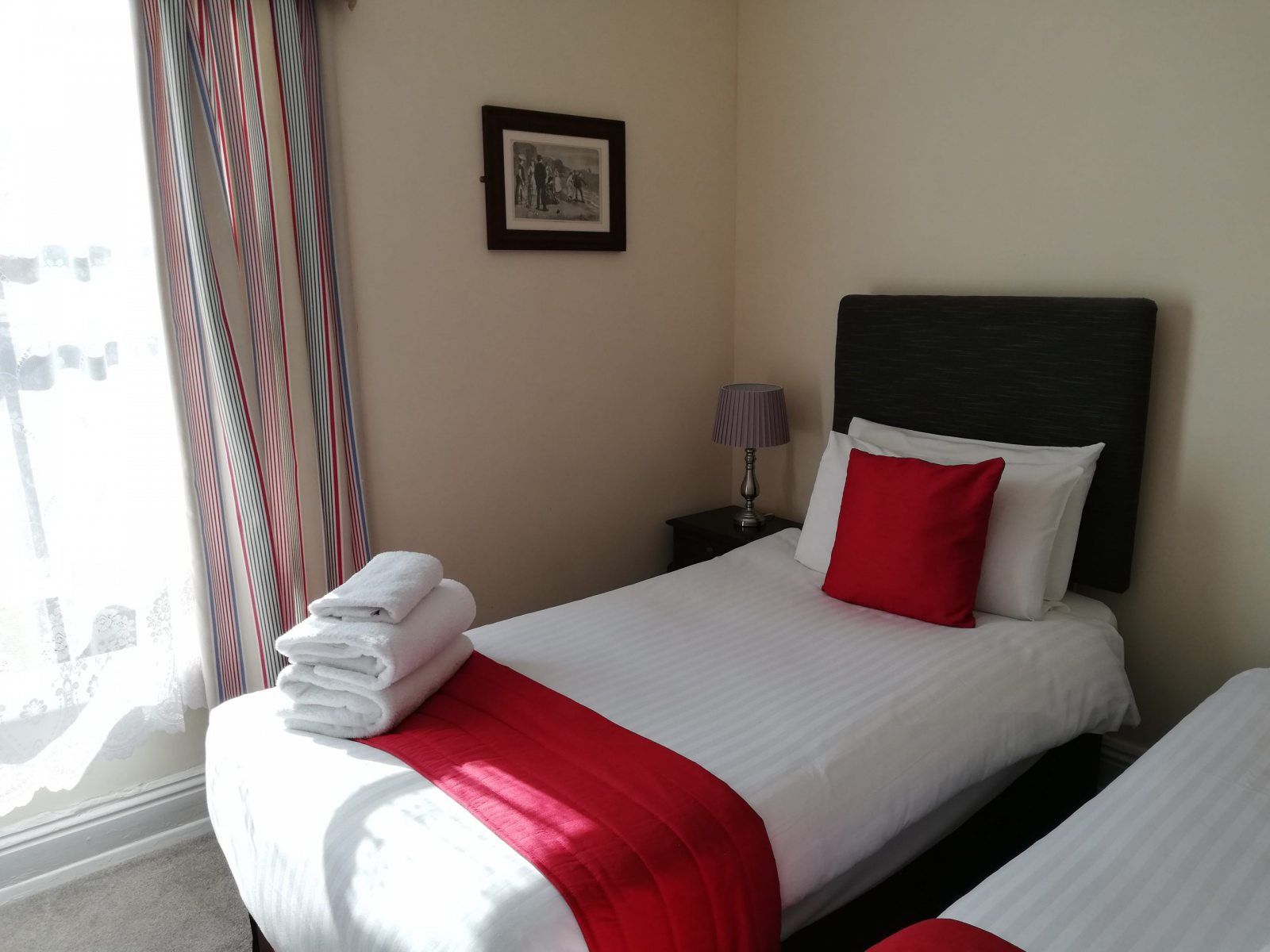 A single room with a red throw beside a tall window