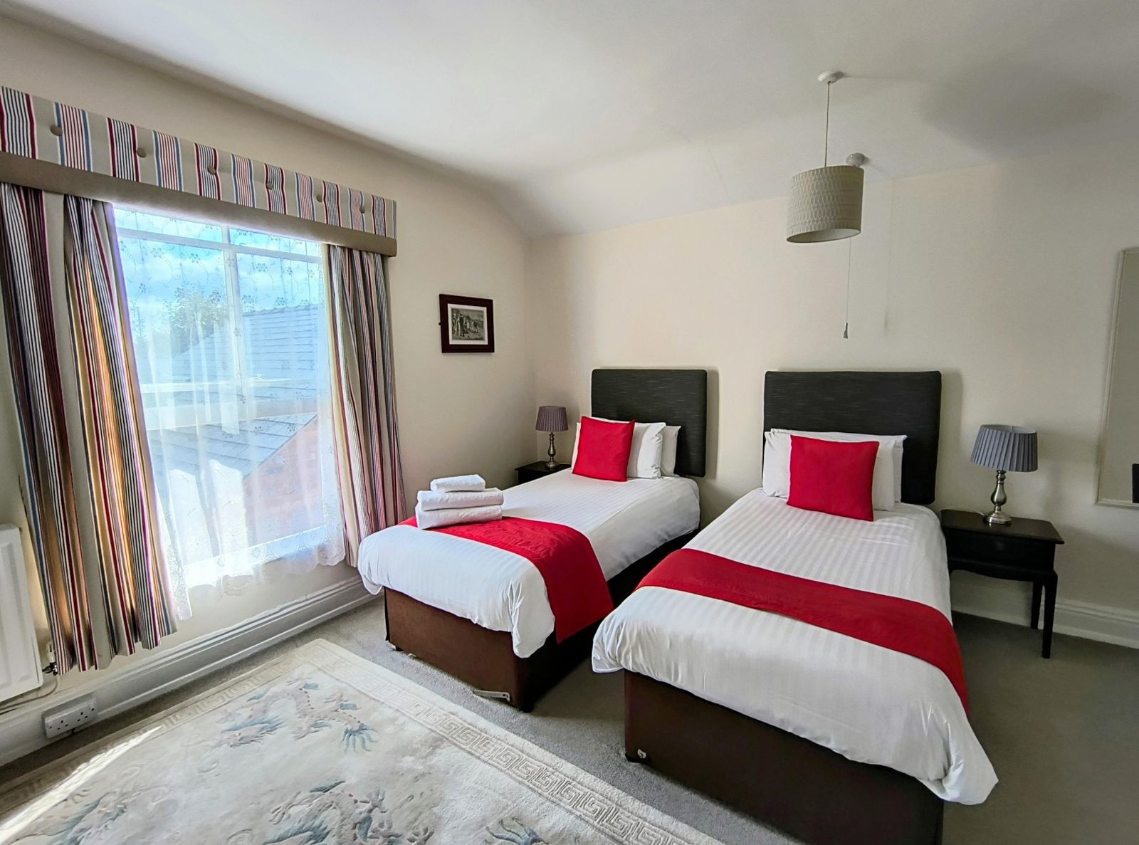 A twin room with two beds and a large bay window